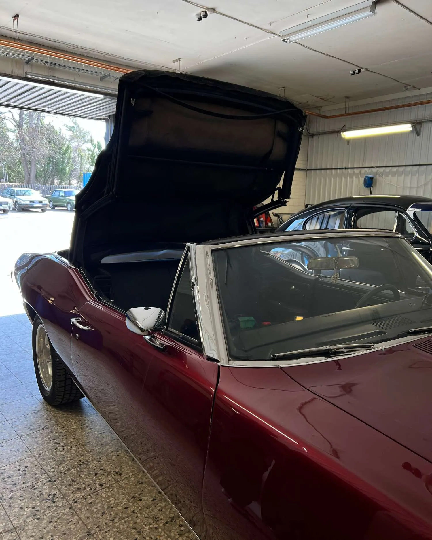 Vinröd cabriolet med uppfällt tak i verkstaden