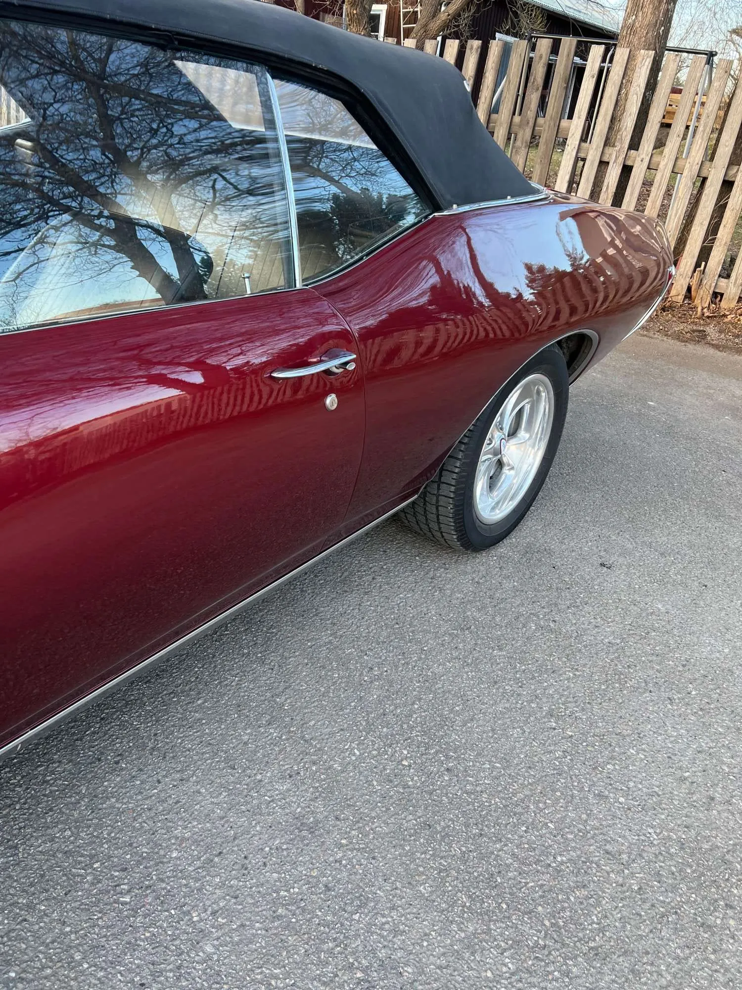 Vinröd cabriolet med svart tak, sedd från sidan