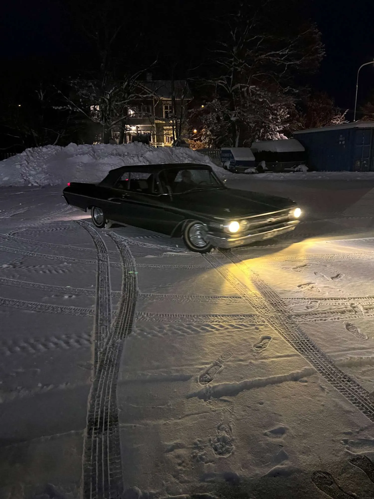 Mörkgrön bil på en snöig gård i vinterkvällen