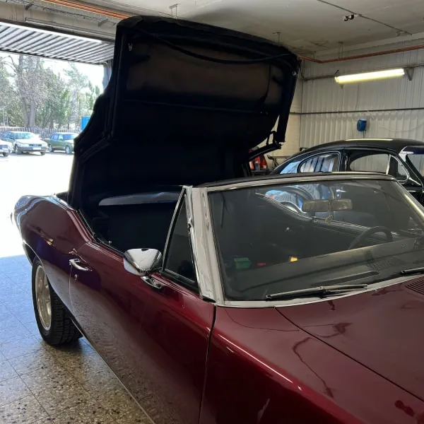 Vinröd cabriolet med uppfällt tak i verkstaden
